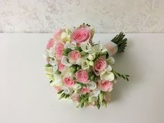 a bouquet of pink and white flowers sitting on top of a table next to a wall