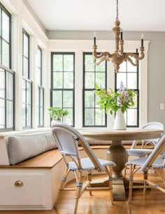 a dining room table with four chairs and a bench in front of the window seat