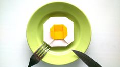 a fork and knife on a plate with origami cubes in the center