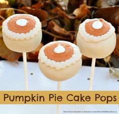 three pumpkin pie cake pops sitting on top of a white table with leaves in the background