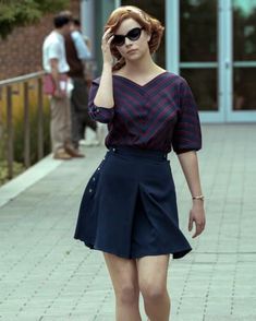 a woman is walking down the street talking on her cell phone while wearing sunglasses and a dress