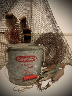 an old metal bucket with some tools in it next to a fishing net and other items