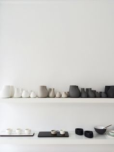 several white and black vases on shelves in a room