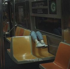 a person sitting on a subway train with their feet up against the seat and legs down