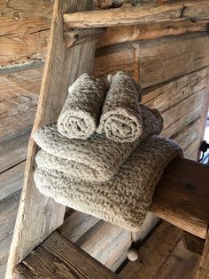 two folded towels sitting on top of a wooden bench in front of a log cabin