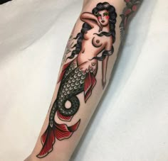 a woman's arm with a mermaid tattoo on it