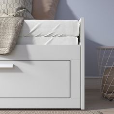 a close up of a bed with a white headboard and night stand on the floor