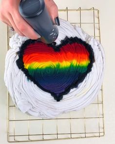 someone is decorating a heart shaped cake on a cooling rack with a remote control