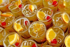 many glasses filled with different types of drinks and garnished with orange slices, cherries, and lemons