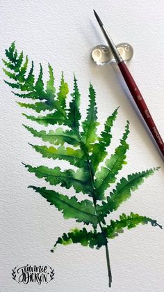 a watercolor painting of a green fern leaf next to a paintbrush and acrylic brush