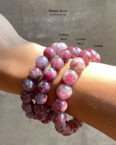 a woman's arm with several bracelets made out of pink and purple beads