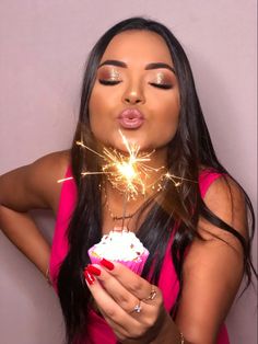 a woman holding a cupcake with sparklers in her mouth