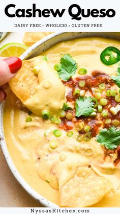 a person dipping tortilla chips into a bowl of quesadilla soup