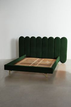 a green bed frame with wooden slats on the bottom and headboard, in front of a white wall