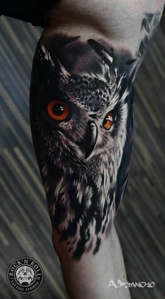 an owl with orange eyes is shown on the leg and it's tattoo design