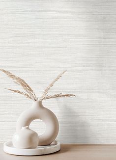 a white vase sitting on top of a wooden table