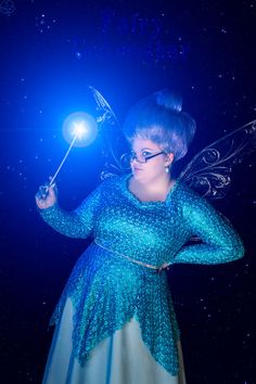 a woman dressed as a fairy holding a light up wand in her right hand and looking at the camera