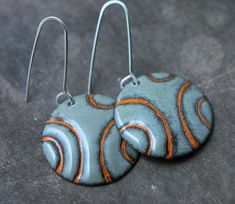 two blue and orange earrings on a gray surface with metal hooks in the shape of circles