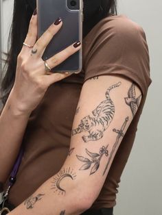 a woman with tattoos on her arm holding a cell phone