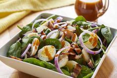 a salad with spinach, hard boiled eggs and onions