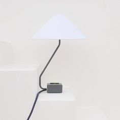 a white lamp sitting on top of a table next to a black and white object