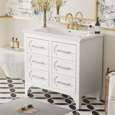 a white bathroom with black and white flooring, gold trim on the mirror above the sink