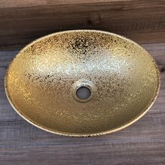 a round gold sink sitting on top of a wooden floor