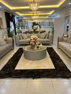 a living room filled with furniture and a chandelier hanging above the coffee table