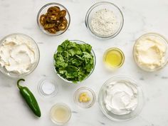 an assortment of ingredients are arranged on a marble counter top, including olives, mayonnaise, and sour cream