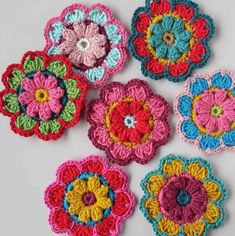 six crocheted flower appliques arranged on a white surface, each with different colors and sizes