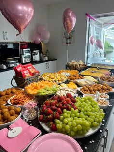 a table filled with lots of different types of food and balloons in the air above it