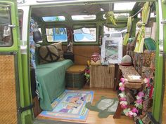 the interior of an old van is decorated with green and white accessories, such as pillows, blankets, rugs, and other items