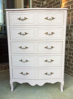 a white dresser sitting in front of a brick wall