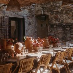 an outdoor dining area with wooden chairs and tables covered in white tablecloths, vases filled with flowers