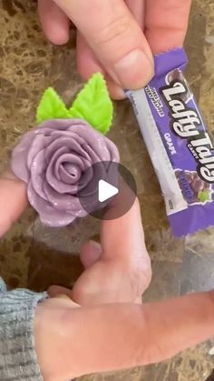 someone is holding a candy bar with a flower on it and another person's hand next to it