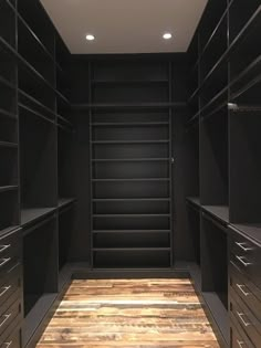 an empty walk - in closet with wooden flooring and black walls, along with dark shelving