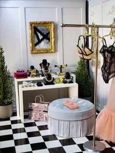 a black and white checkered floor with clothes hanging on racks, an umbrella stand, and a pink dress