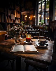 an open book sitting on top of a wooden table next to a cup of coffee