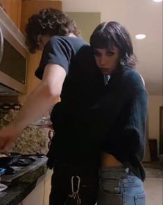 two people standing in a kitchen preparing food