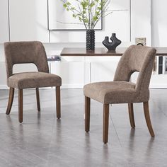 two chairs sitting at a table in front of a vase with flowers on top of it