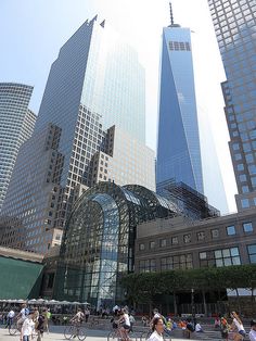 many people are riding bicycles in front of some tall buildings with glass windows on them