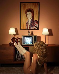 a woman sitting on the floor in front of a tv with her legs crossed and feet up