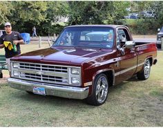 a man standing next to a red pickup truck