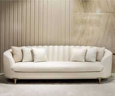 a white couch sitting in front of a wall with pillows on it's back