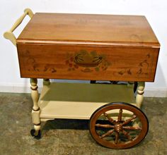 an old wooden cart with wheels on the bottom and painted flowers on the front, sitting in a room