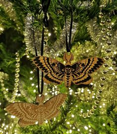 two wooden moths hanging from a christmas tree