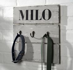 two leashes are hanging on the wall next to a sign that says milo