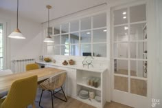 a dining room table with yellow chairs and white walls