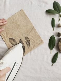 a person is holding a paper bag with leaves and mushrooms on the table next to them