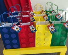 bags made out of legos sitting on top of a yellow table with red, green, blue and yellow handles